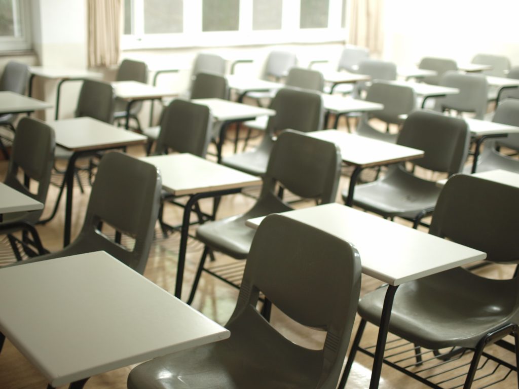 Tyhjä koululuokka: tuoleja ja pöytiä.