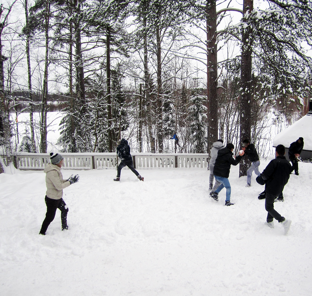 Lapsia leikkimässä pihalla lumisessa maisemassa