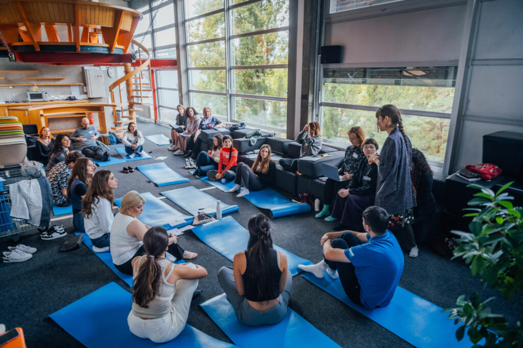 People sitting at blue yoga mats.